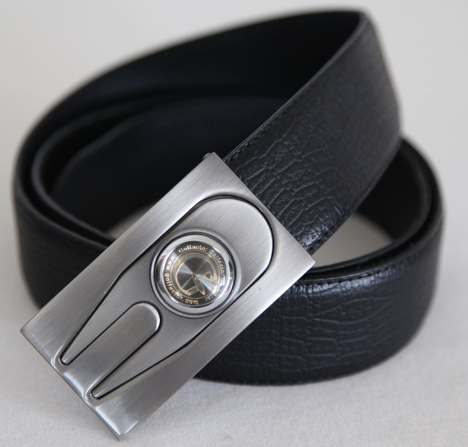 A black leather golf belt whose metal buckle holds a ball marker and a divot tool