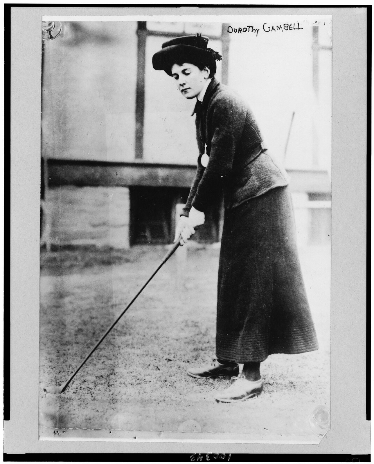 Dorothy Campbell in 1909, swinging in a long skirt, fitted jacket, collar and hat