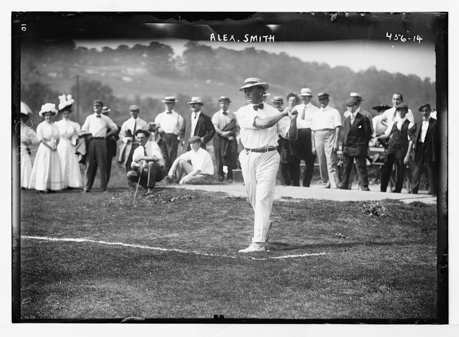 Alex Smith driving in shirt and tie in 1908, watched by a gallery in jackets, hats and long dresses