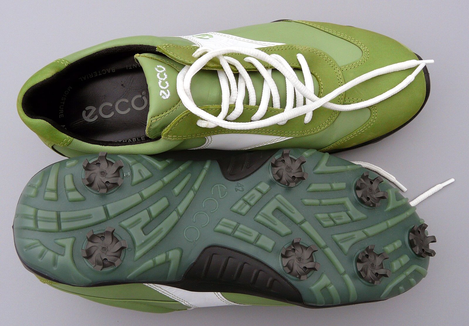 A pair of green ECCO golf shoes, one showing the sole and its plastic spikes