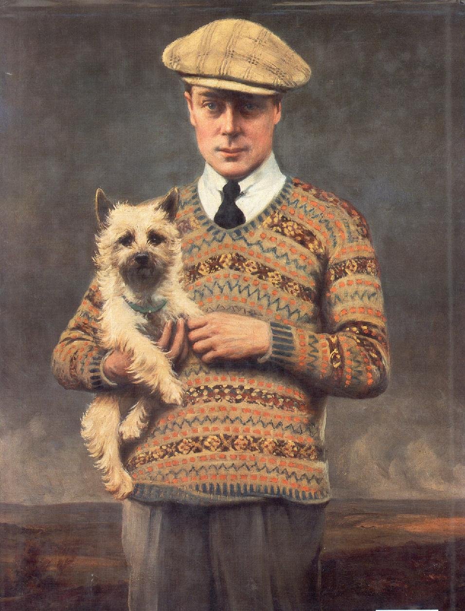 Portrait of the Prince of Wales in a flat cap and a patterned Fair Isle sweater, holding a terrier