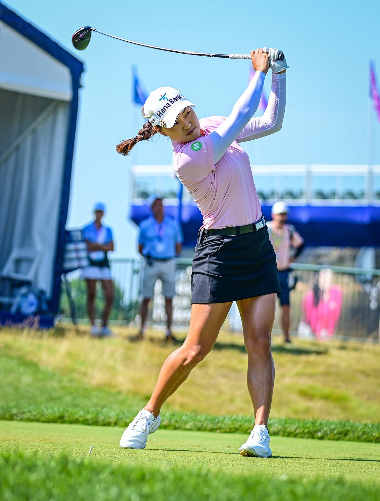 Minjee Lee teeing off at the 2022 KPMG Women's PGA Championship in white sun sleeves under a pink collared top, with a navy skirt