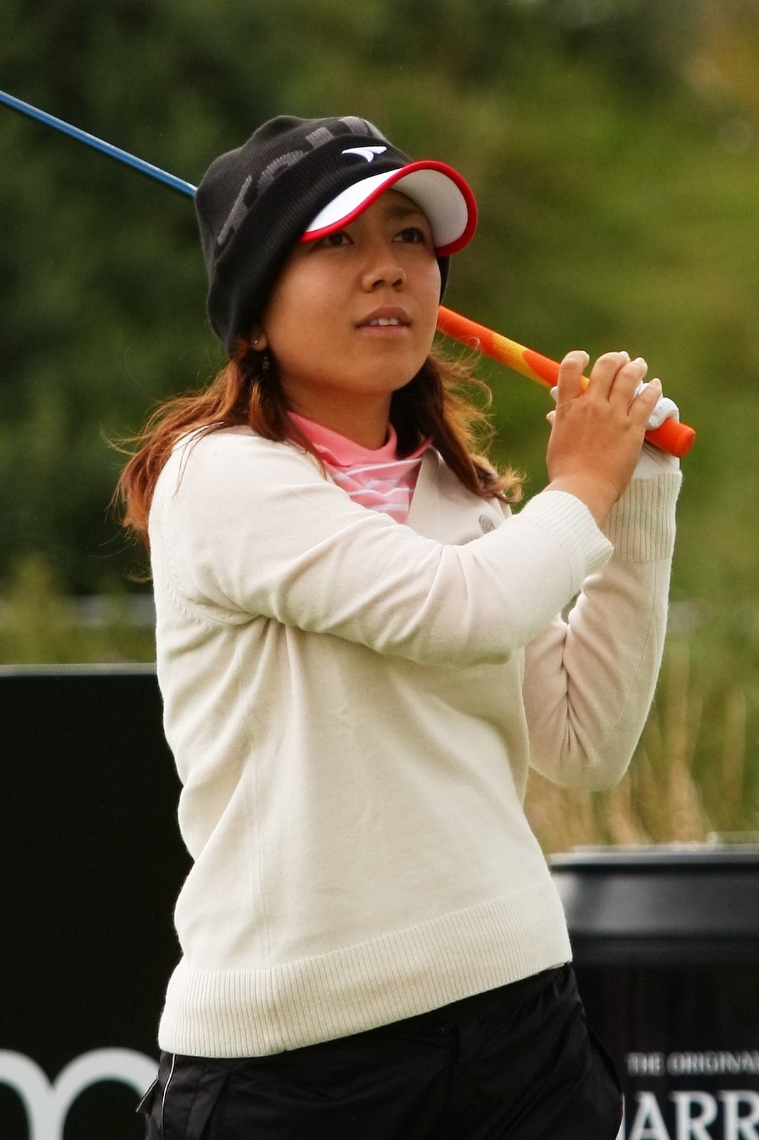 Mika Miyazato at the 2010 Women's British Open in Southport, layered in a cream sweater over a pink mock neck, with a knit beanie under her cap