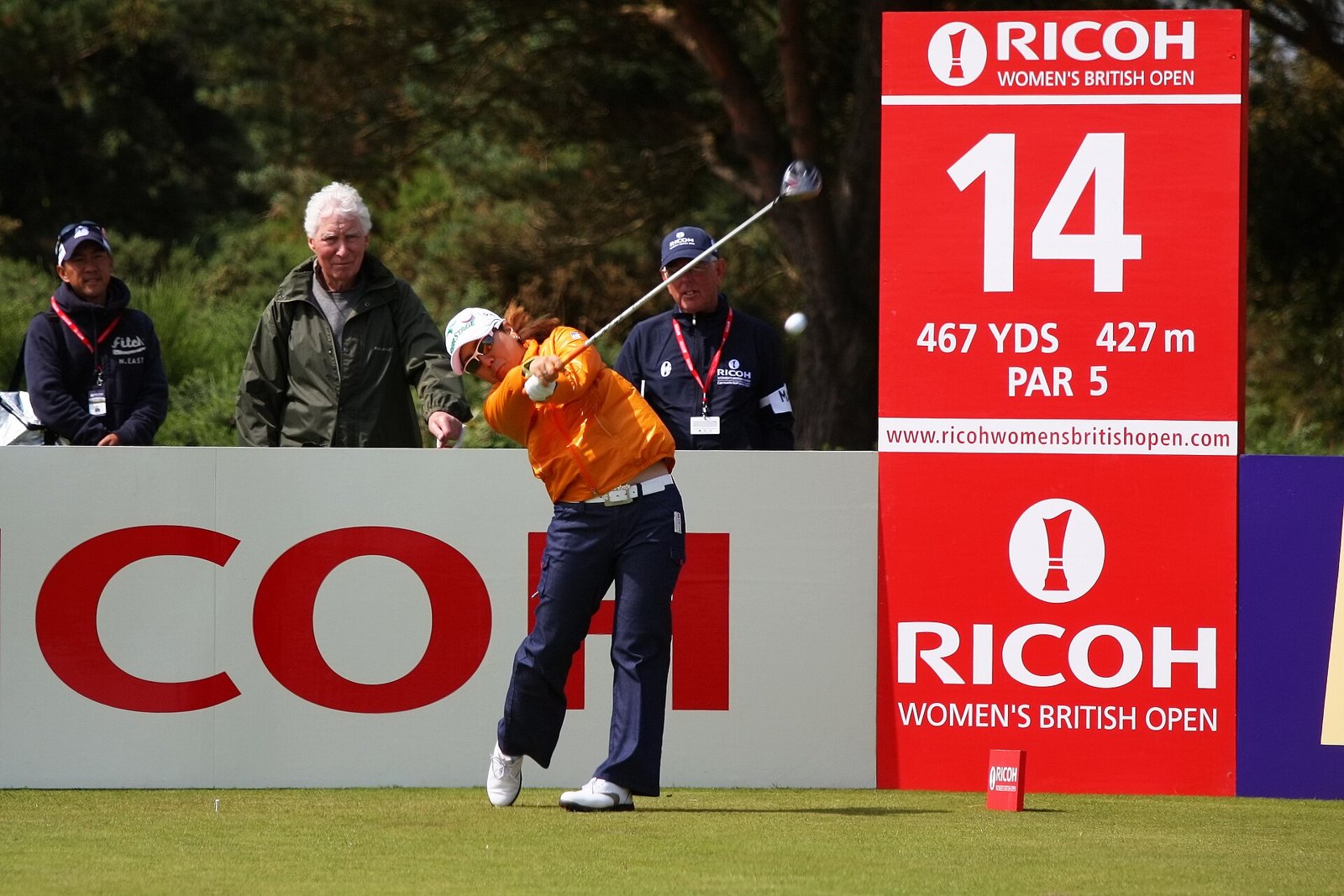 Mika Miyazato driving at the 2011 Women's British Open in navy pants, a white belt and an orange top